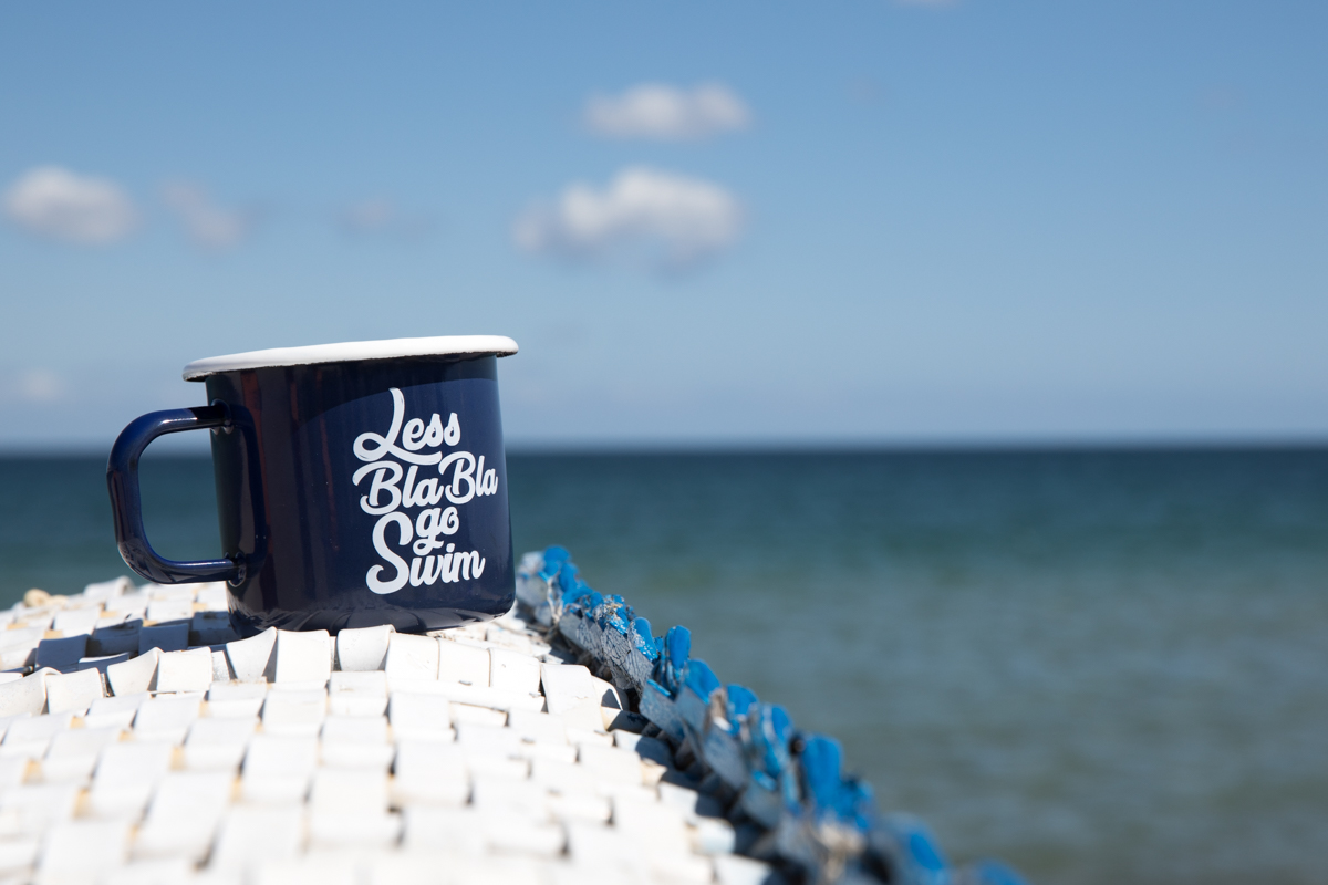 Bedruckter Emaille Becher in Blau mit weißem Rand am Meer